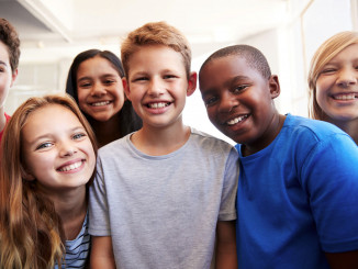 Portrait Of Smiling Male And Female Students In Grade School Classroom