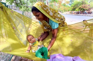 A daily wager woman labourer puts her child in a make-shift cradle made of cloth at her work site on the eve of Mother's Day in Bhopal.