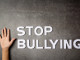 word-stop-bullying-with-child-s-hand-dark-wall