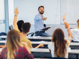 Group of students raising hands in class on lecture
