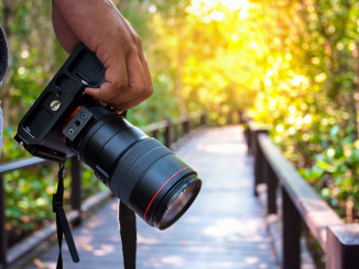 Man holding his camera on walkway during his travel