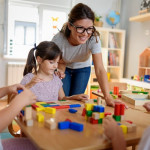 Preschool teacher with children playing with didactic toys