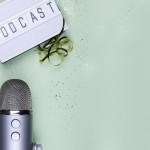 Top view photo of podcast concept - lightbox with letters podcast on it, headphones and professional microphone