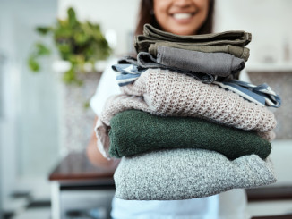 Closeup shot of a young woman holding a pile of folded laundry at home