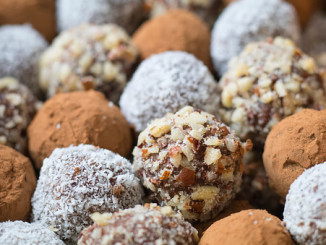 Hazelnut, cocoa, coconut and date homemade balls, lined up in rows.